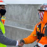 On the deck of a concrete structure, USDOT FRA Deputy Administrator Amit Bose shakes the hand of Adrian Pacheco, a carpenter helping build the nation's first high-speed rail system.