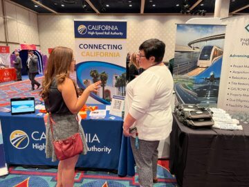 Two women speaking in front of an outreach booth.